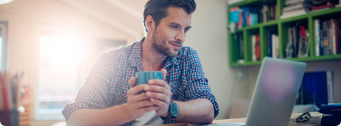 man holding mug looking at computer